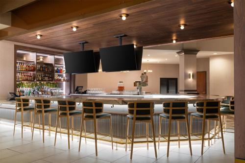 a bar with chairs and a large island in a room at Embassy Suites by Hilton at Hot Springs Convention Center in Hot Springs