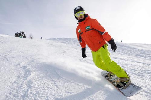 a man riding a snowboard down a snow covered slope at Appartements Herwig Schwarzenbacher in Weissensee