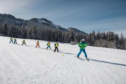 a group of people skiing down a snow covered slope at Appartements Herwig Schwarzenbacher in Weissensee