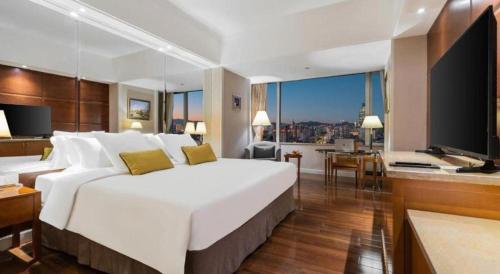a hotel room with a large white bed and a television at Kai Wah Plaza International Hotel in Kunming