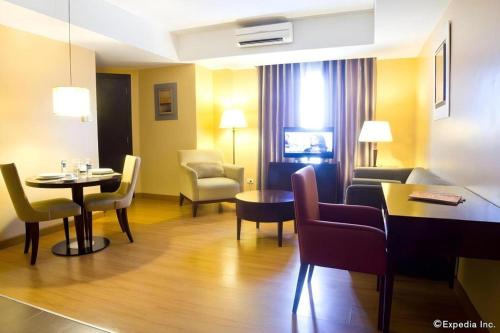 a living room with a table and chairs in a hotel room at Lancaster Hotel Manila in Manila