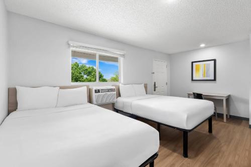 two beds in a room with a window at Birch Hill Suites - Lakeland in Lakeland