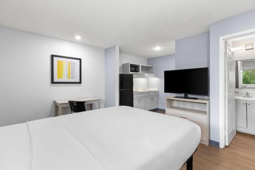 a bedroom with a white bed and a flat screen tv at Birch Hill Suites - Lakeland in Lakeland