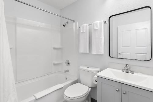 a white bathroom with a sink and a toilet and a mirror at Birch Hill Suites - Lakeland in Lakeland