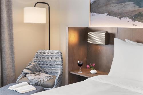 a bedroom with a bed and a chair with a glass of wine at Starlite Yellowstone, Tapestry Collection by Hilton in West Yellowstone