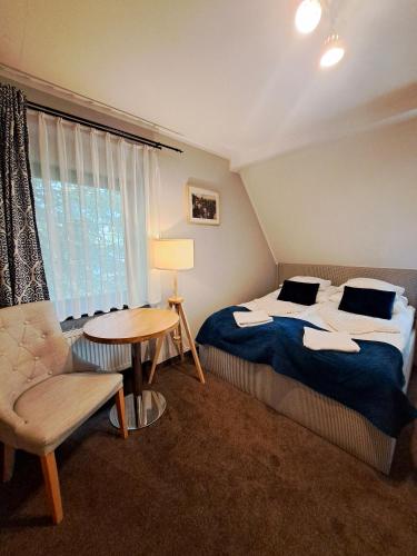 a bedroom with a bed and a table and a chair at Pensjonat Pod Świerkami in Polanica-Zdrój