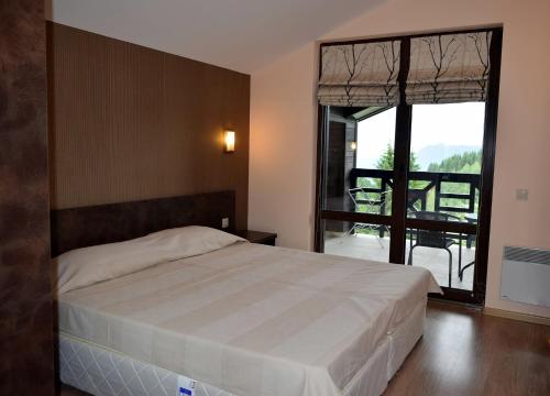 a bedroom with a large bed and a large window at GOLDI 85 in Pamporovo