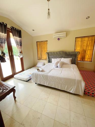a bedroom with a large white bed and two windows at Vila Princess Sentul 7 bedroom Private pool, Billiard, Tenis meja in Babakan Madang