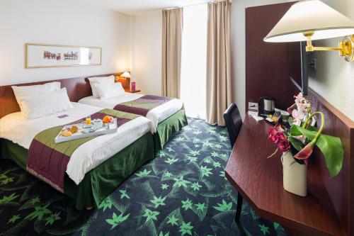 a hotel room with a bed with a tray of food on it at Mercure Lourdes Impérial in Lourdes
