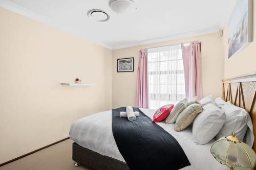 a bedroom with a bed with pillows and a window at Tranquil Queen Room - Centrally Located at Milperra - Shared Bathroom in Panania
