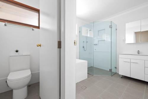 a bathroom with a toilet and a glass shower at Tranquil Queen Room - Centrally Located at Milperra - Shared Bathroom in Panania
