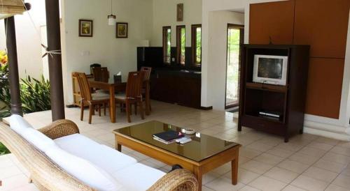 a living room with a couch and a table and a tv at Tanjung Lesung Beach Hotel in Carita