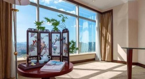 a room with a table and a large window at New Century Grand Hotel Zhuji Yaojiang in Shaoxing