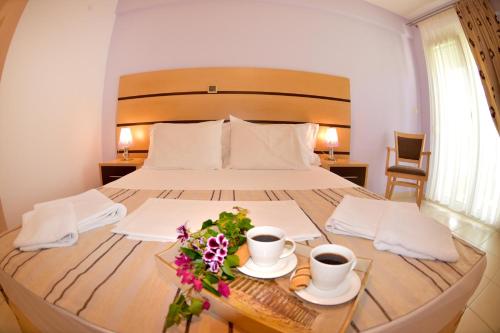 una camera da letto con un letto con due tazze di caffè e fiori di Phoenix Studios by Tania a Sárti