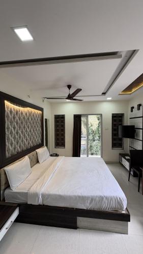 a bedroom with a large bed with a ceiling fan at New White House Hotel in Pune