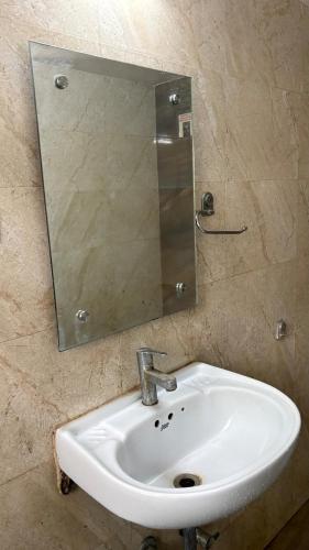 a bathroom sink with a mirror on a wall at New White House Hotel in Pune