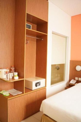 a bedroom with a bed and a window and a microwave at Pomelotel Patra Kuningan Jakarta in Jakarta