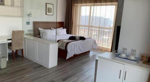 a bedroom with a bed with a desk and a window at GreenTree Inn Weihai Liugongdao Wharf Qingdao North Road Express Hotel in Weihai
