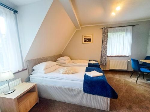 a bedroom with a large bed with a blue blanket at Pensjonat Pod Świerkami in Polanica-Zdrój