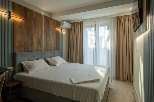 a bedroom with a bed with white sheets and a window at AER Apart & Wine in Eforie