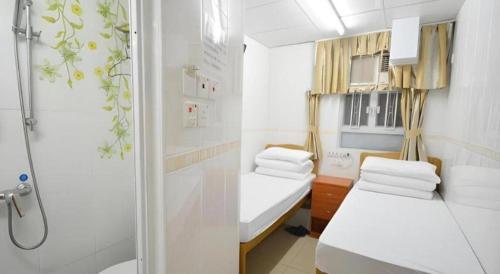 a small bathroom with two beds and a shower at New Mong Kok Guest House in Hong Kong