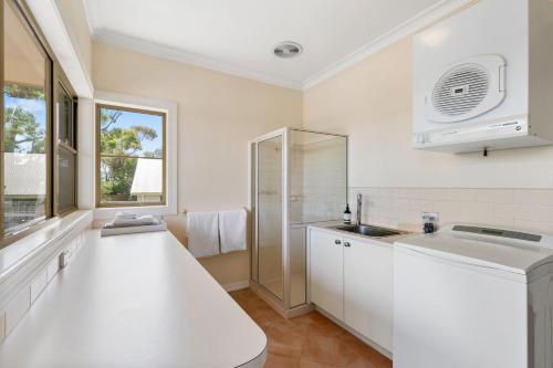 Una cocina blanca con fregadero y ventana. en Sea Breeze on the Crescent, en Inverloch
