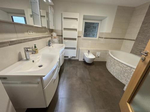 a bathroom with two sinks and a tub and a toilet at Traumpanorama zwischen Chiemsee und Salzburg - 74 qm - mit E-Ladesäule in Surberg