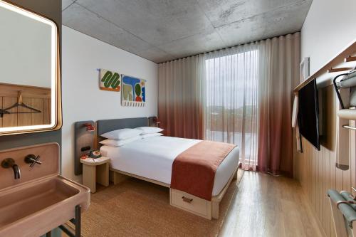 a bedroom with a bed and a sink and a tub at Moxy Sydney Airport in Sydney