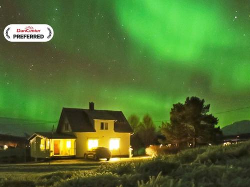 an image of a house under the northern lights at 6 person holiday home in Storsteinnes in Storsteinnes