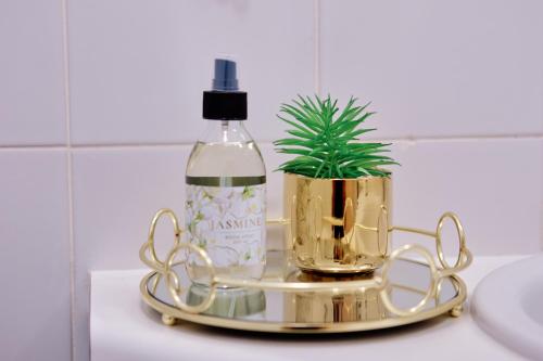 Un frasco de perfume y una planta en una bandeja de oro. en Seaview Haven - Luxury Coastal Escape Simon's Town, en Simonʼs Town