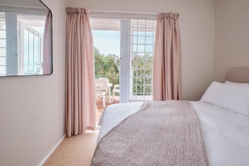 Un dormitorio con una cama y una ventana grande. en Seaview Haven - Luxury Coastal Escape Simon's Town, en Simonʼs Town