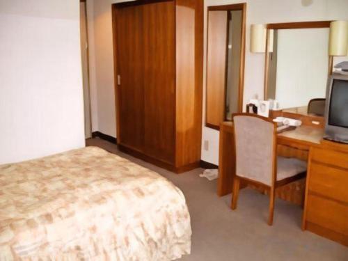 a hotel room with a bed and a desk and a television at Hotel Ito in Wakayama