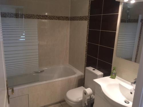 a bathroom with a tub and a toilet and a sink at Maison Tobias in Bussy-Saint-Georges
