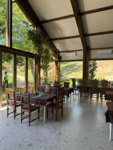 a dining room with tables and chairs and large windows at Eko Zaseok Brana in Rekovac
