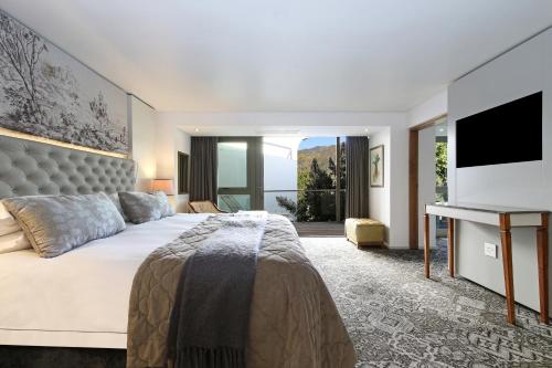 a bedroom with a large bed and a television at Vineyard Hotel in Cape Town