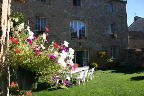 a table and chairs in front of a building with flowers at Chambres D’hôtes Lou Jassou in Lapanouse-de-Cernon