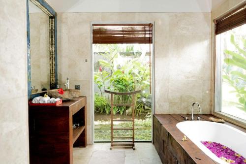 a bathroom with a tub and a large window at Villa Fleur in Tumbak Bayuh