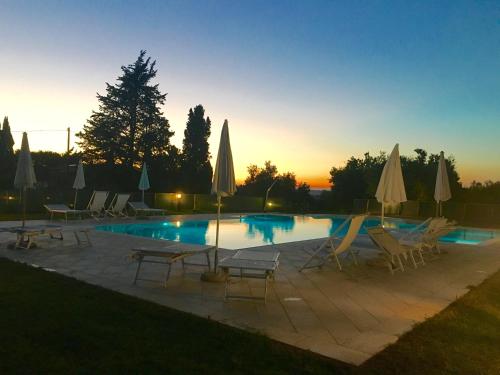 a swimming pool with chairs and umbrellas at sunset at Agriturismo L'Antica Quercia in Pomarance