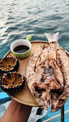 a person holding a plate of food and a cup of coffee at Lungkluay homestay in Ko Kood