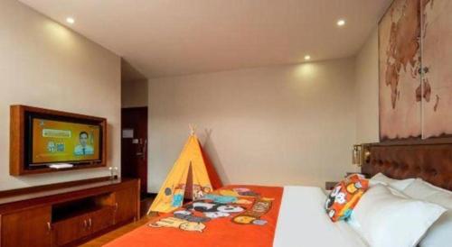 a bedroom with a bed with a television on a wall at James Joyce Coffetel·Lijiang Old Town Centeral in Lijiang