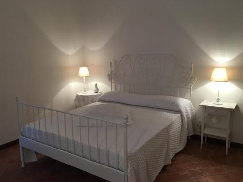 a bedroom with a white bed with two tables and two lamps at Appartamento Michelangeli-Private parking in Orvieto