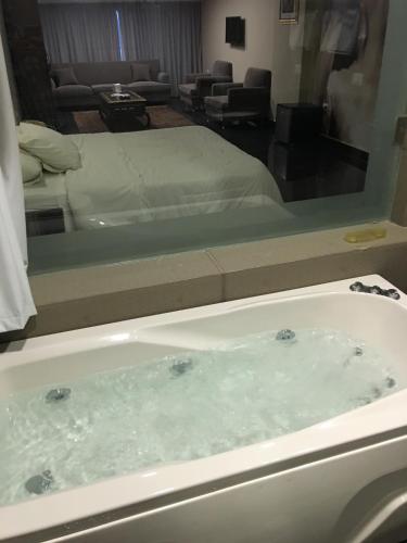 eine Badewanne in einem Hotelzimmer mit einem Bett in der Unterkunft Platinum Hotel in Tyros