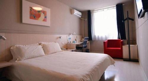 a bedroom with a white bed and a red chair at Jinjiang Inn Yantai Fushan District Fuhai Road in Yantai