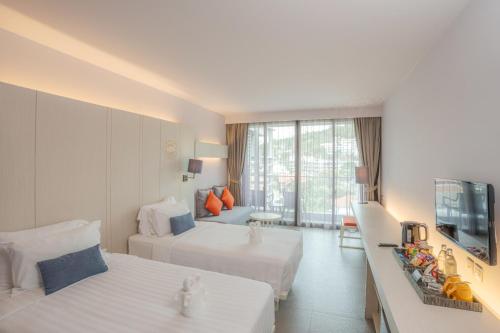 a hotel room with two beds and a television at The Yama Hotel Phuket in Kata Beach