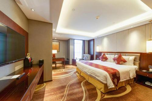 a hotel room with a large bed and a flat screen tv at New Century Grand Hotel Xi'an Xizang Building in Xi'an