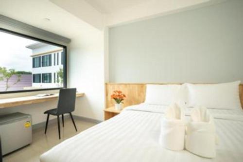 a bedroom with a white bed with a desk and a window at Meesuk ChiangRai Hotel in Chiang Rai
