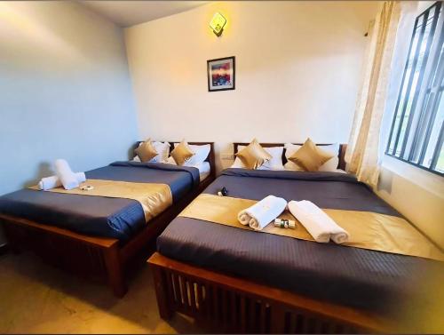 two twin beds in a room with a window at Humming Bird By Brown Tree Resorts in Kotagiri