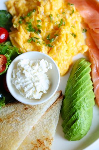a plate of breakfast food with eggs and a sandwich at Palmira Hotel Bishkek in Bishkek
