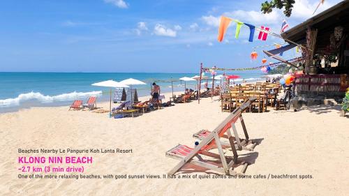 a beach with chairs and umbrellas and the ocean at Le Panpurie Koh Lanta Resort in Ko Lanta Yai