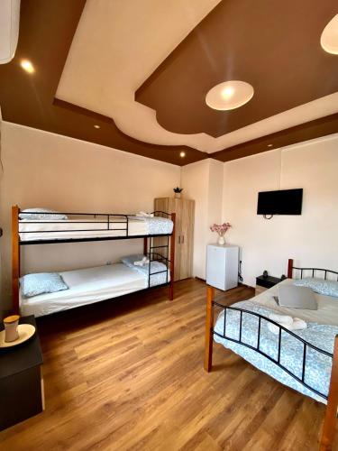 a room with three bunk beds and a flat screen tv at Helena Hostels in Kostinbrod